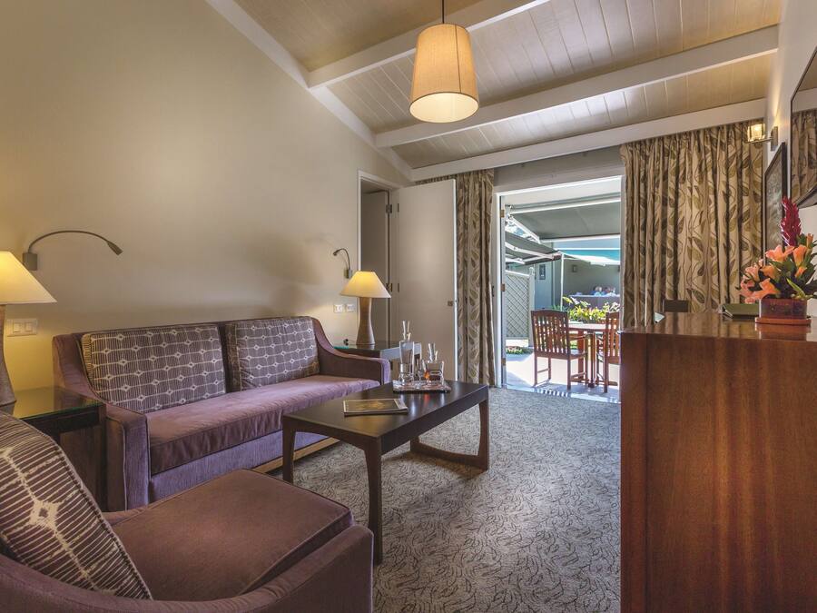 Habitación de hotel con sofá, mesa de centro, lámpara, televisor y vistas al exterior.