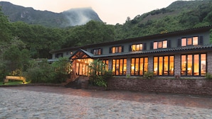 A traditional building with a stone facade, large windows, and a stone staircase leading to the entrance.