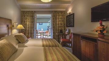 A hotel room with a large bed, a desk, a chair, and a view of the outside.
