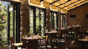 A restaurant with stone walls, large windows, and tables set for dining.