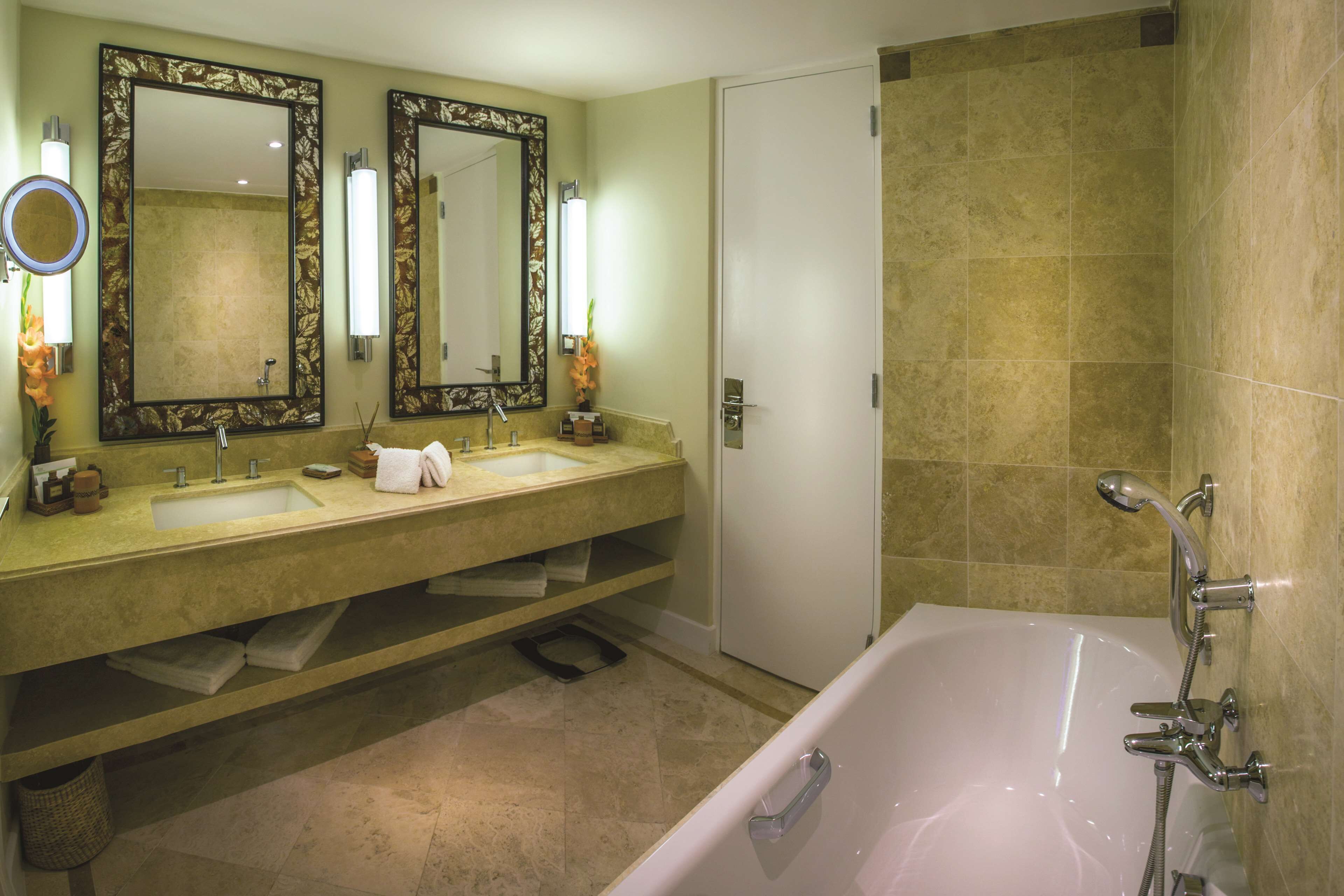 Un baño con bañera, dos lavamanos, un espejo grande y una puerta.
