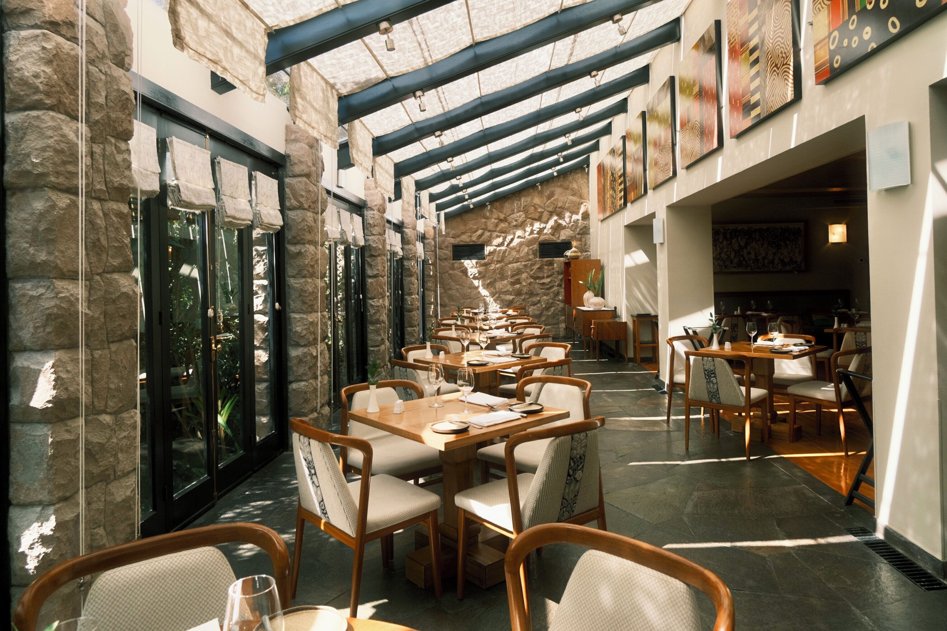 A restaurant with stone walls, wooden tables, and chairs.
