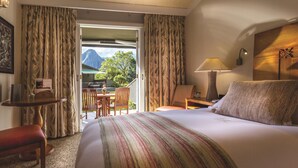 A hotel room with a bed, a desk, a chair, a table, a lamp, and a view of the outdoors.