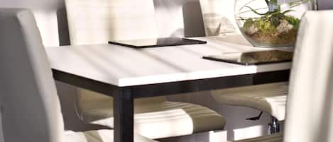 A modern dining area with a table, chairs, a pendant light, and a framed picture of a building.