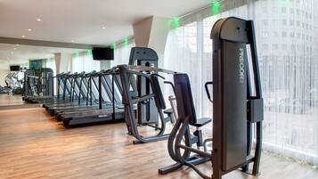 A gym with treadmills, weight machines, and a large mirror.
