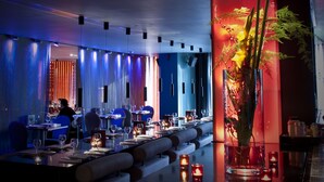 A modern restaurant with a long dining table, candles, and a decorative plant. - Park Plaza Leeds (Leeds)