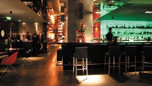 A bar area with bar stools, a counter, and shelves of bottles. - Park Plaza Leeds (Leeds)
