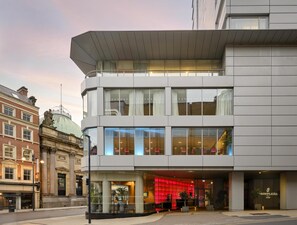 A modern hotel with a glass facade, a red-lit entrance, and a classical building adjacent to it. - Park Plaza Leeds (Leeds)