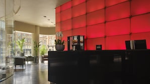 A reception area with a red wall, a black reception desk, and potted plants. - Park Plaza Leeds (Leeds)