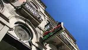 A building facade with a circular window and a sign with red and green colors. - Costa do Sol Residencial (Porto)