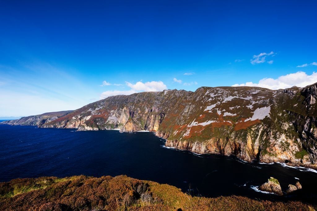 A coastal landscape with rugged cliffs and a clear blue sky.