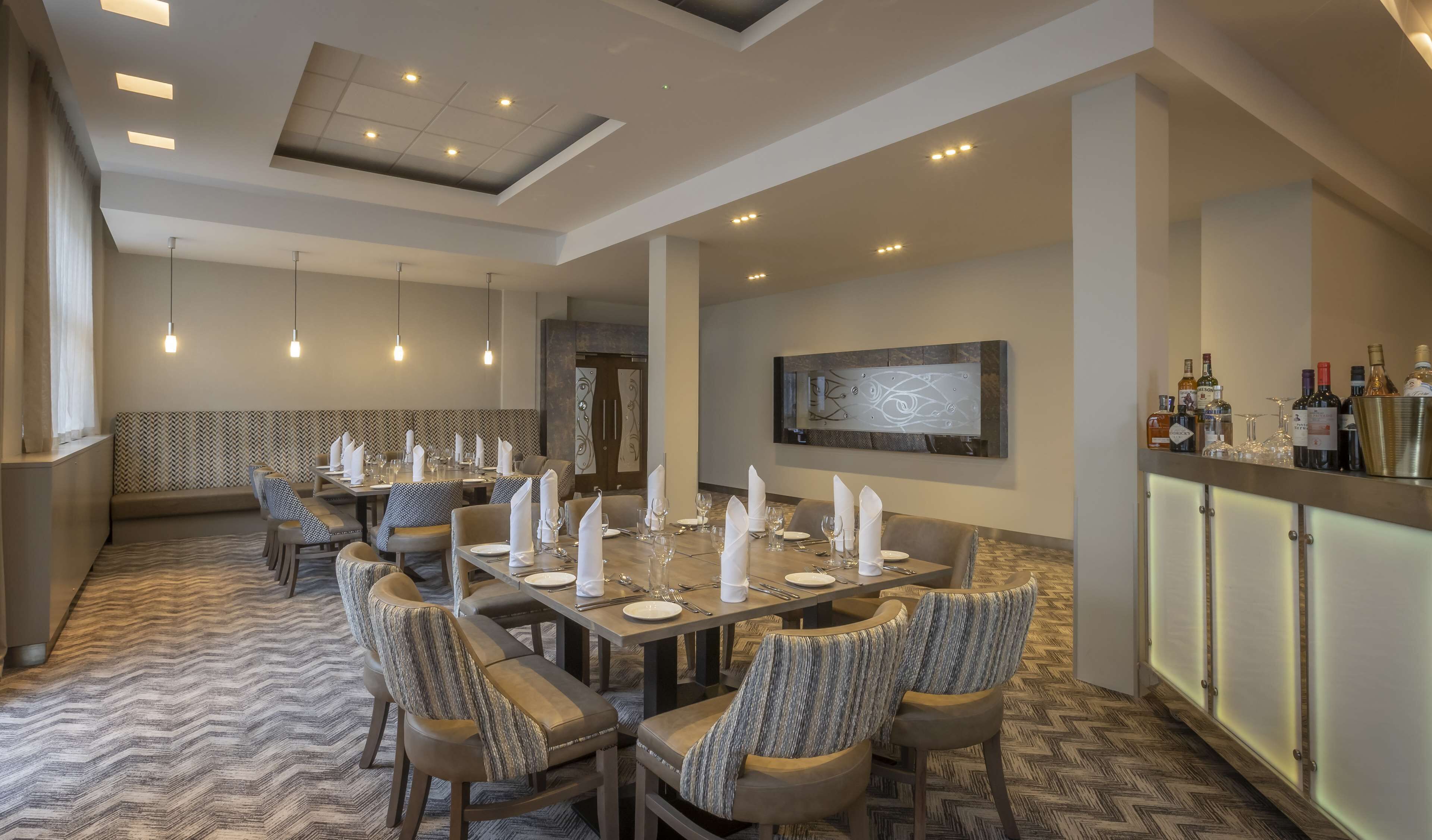 A dining area with a long table set for a meal, surrounded by upholstered chairs.