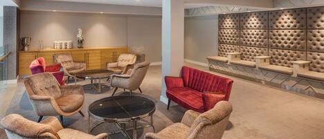A modern lounge area with comfortable seating, a central coffee table, and a decorative wall with a geometric pattern.