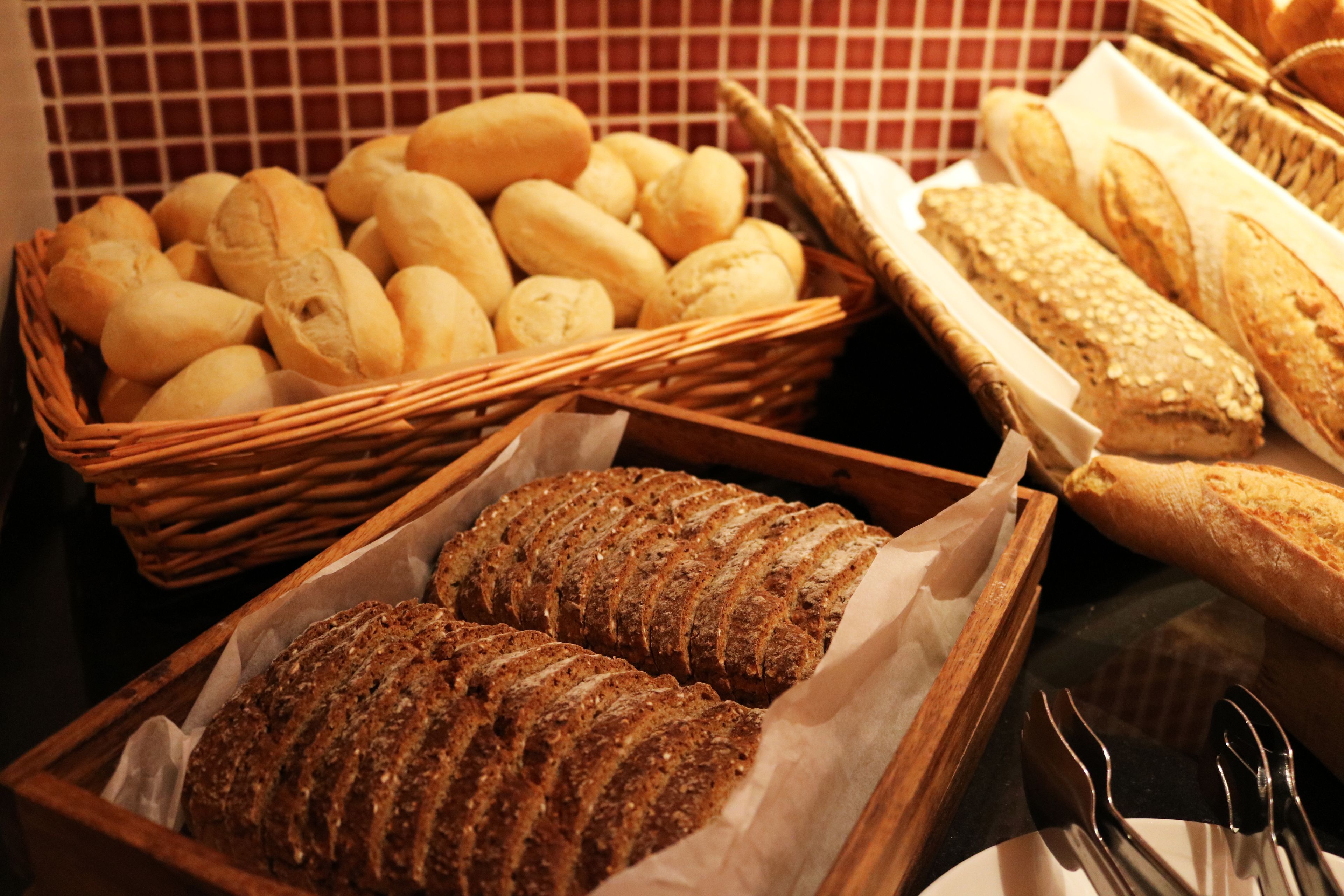 A variety of breads in wicker baskets and wooden trays.
