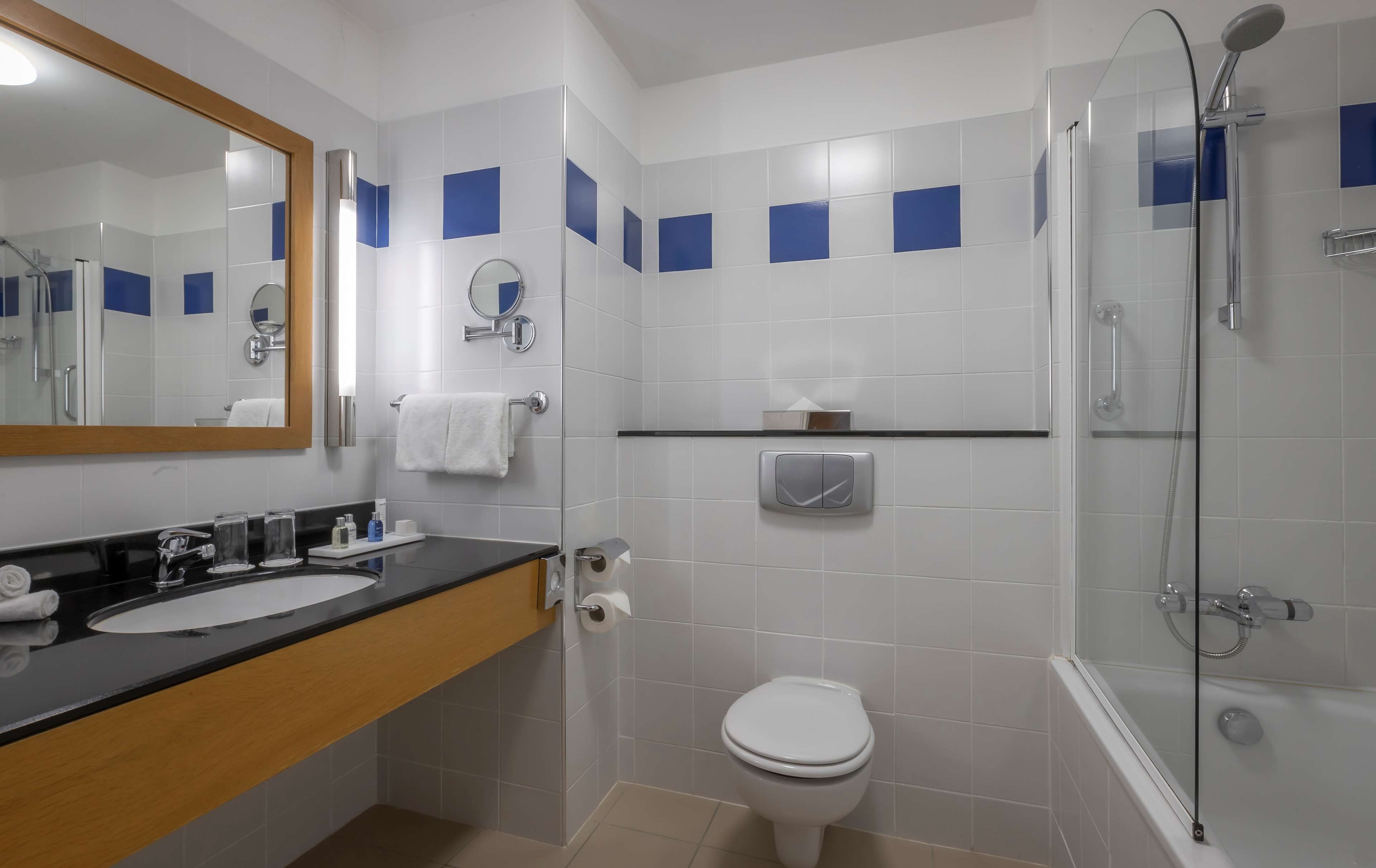A modern bathroom with a black countertop, white sink, and a glass-enclosed shower.
