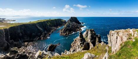 A coastal landscape with rocky cliffs and a clear view of the sea.