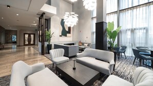 A spacious lobby with modern furniture, large windows, and decorative lighting.