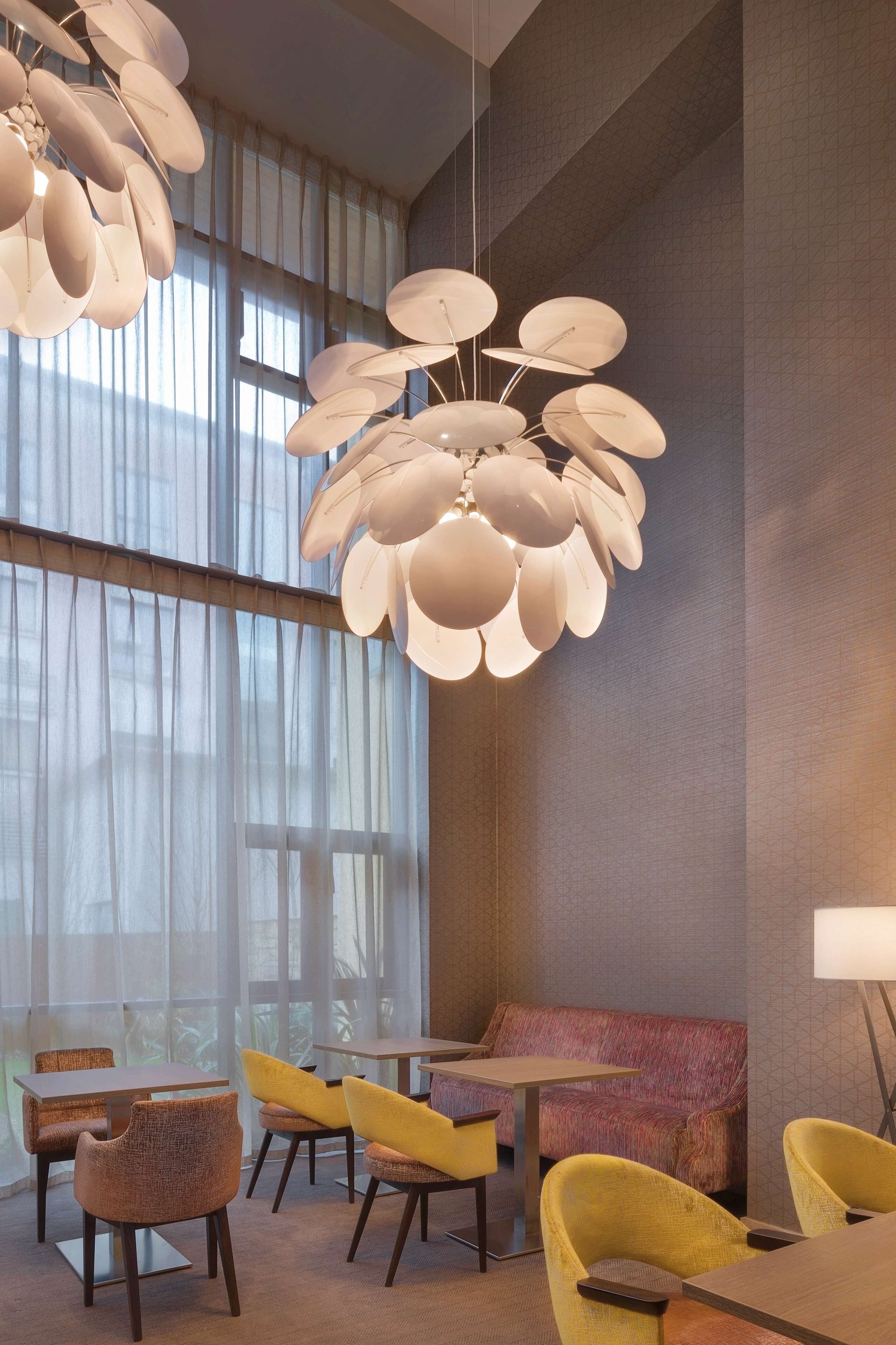 A modern interior with a unique ceiling light fixture, comfortable seating, and large windows allowing natural light.