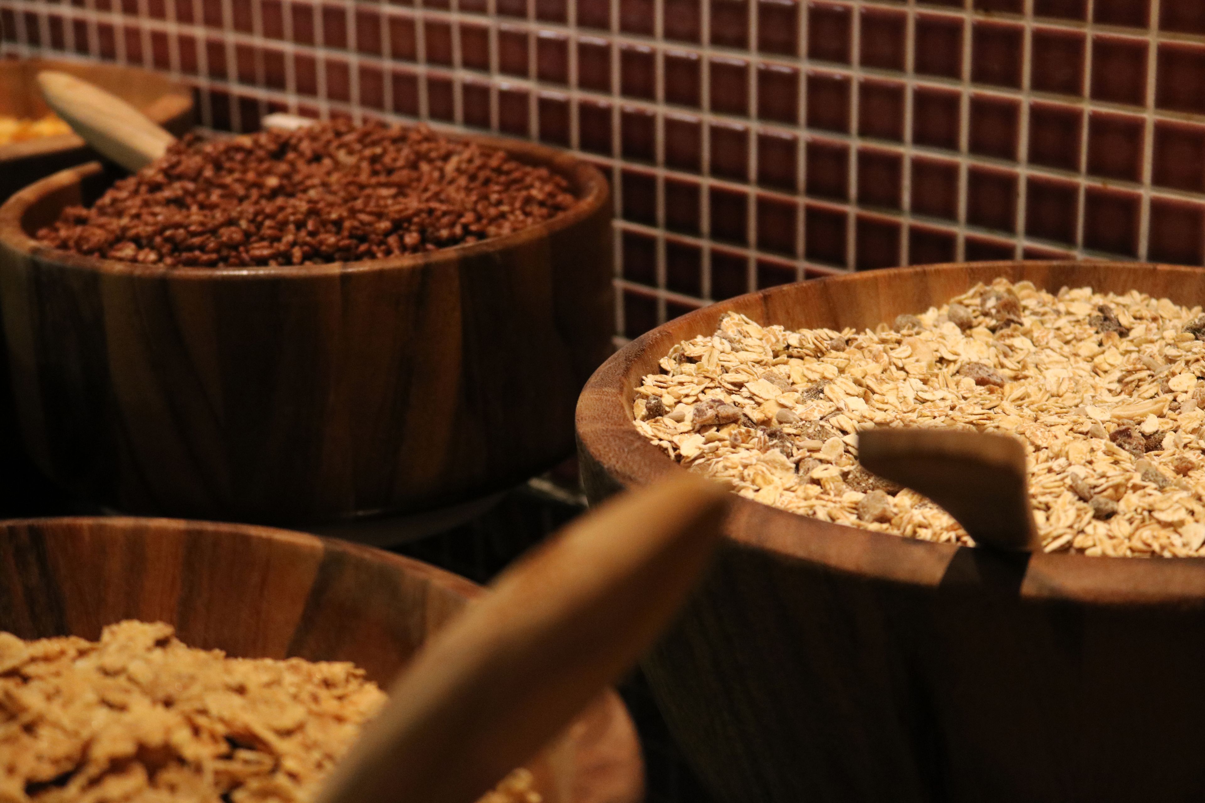 Tres tazones de madera con diferentes cereales y avena.