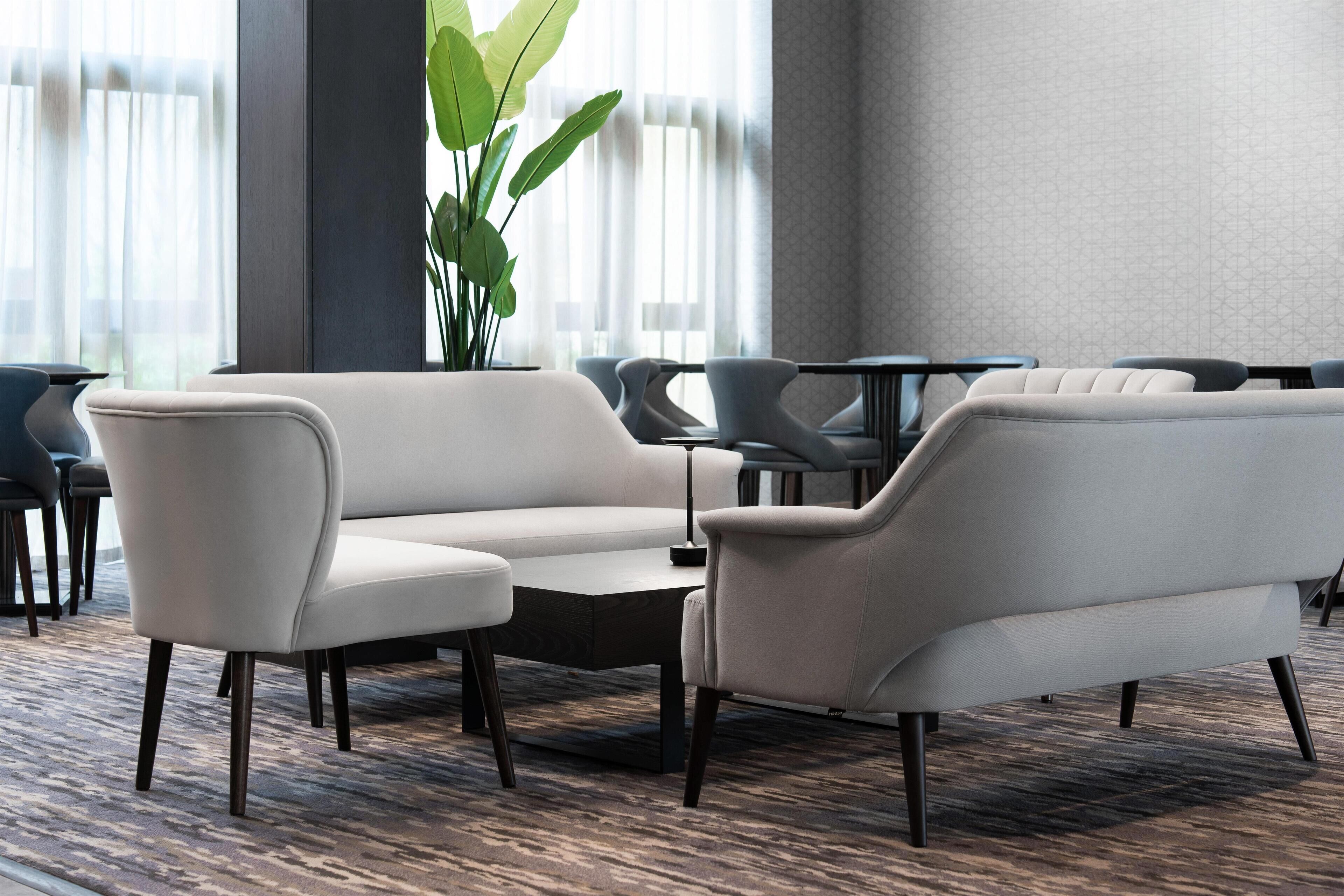 Ein stilvoller Lounge-Bereich mit Ecksofa, Couchtisch und einer Topfpflanze.