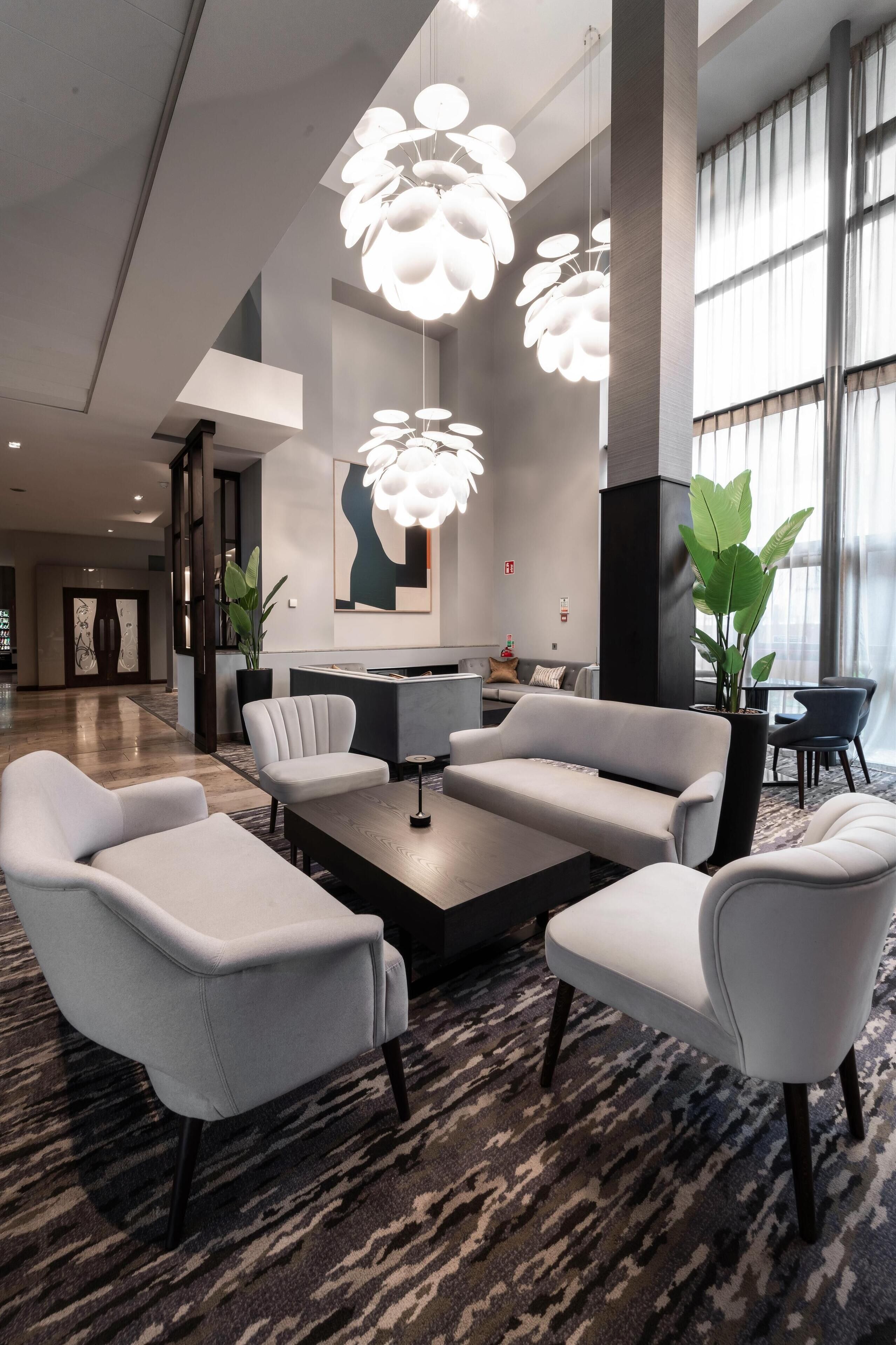 Un vestíbulo moderno con una recepción, zona de estar y ventanas amplias.