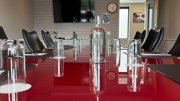 A conference room with a red table, clear glass bottles, and black chairs.