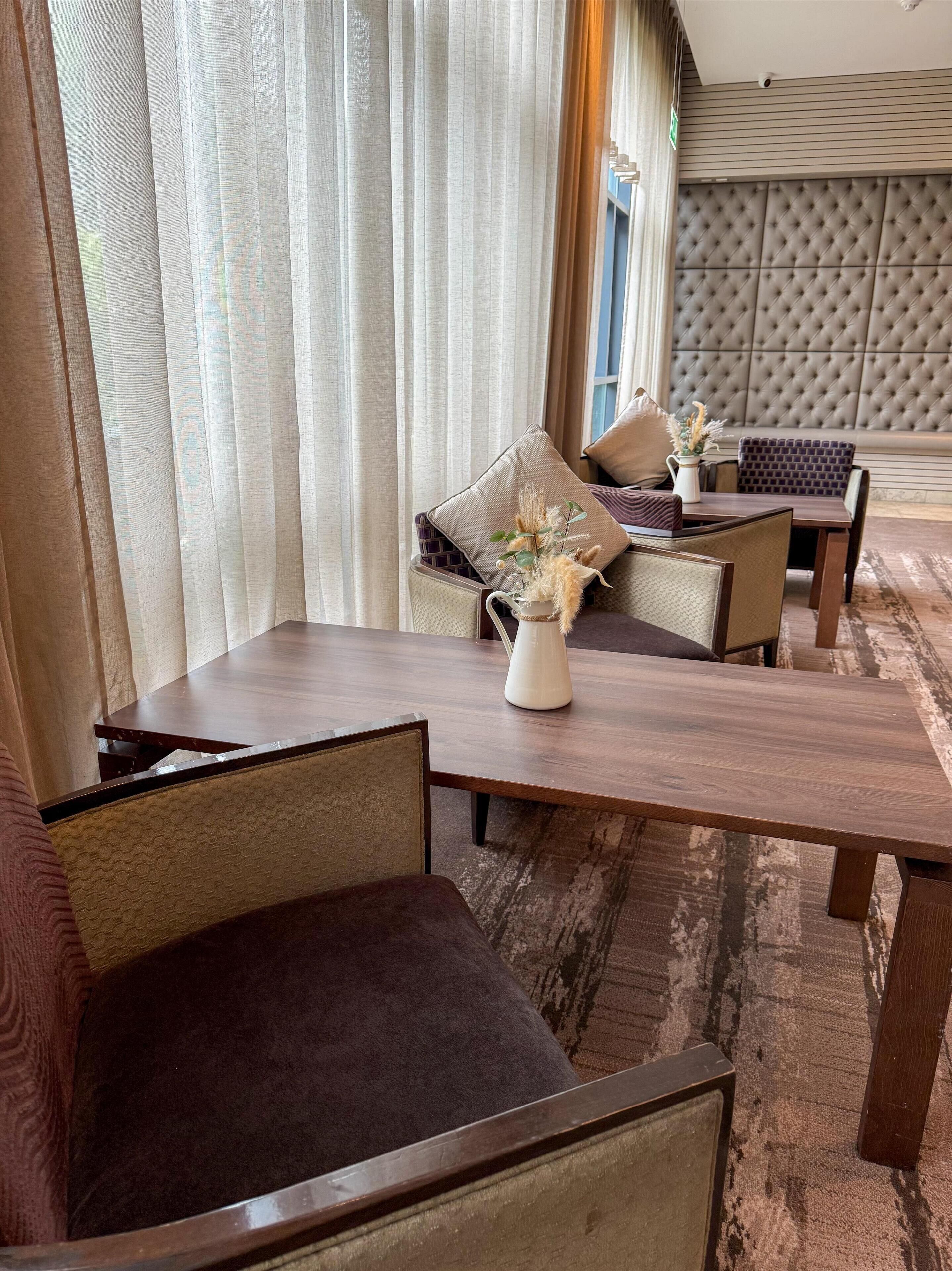Un salon moderne avec une table basse en bois, des sièges confortables et un vase décoratif.