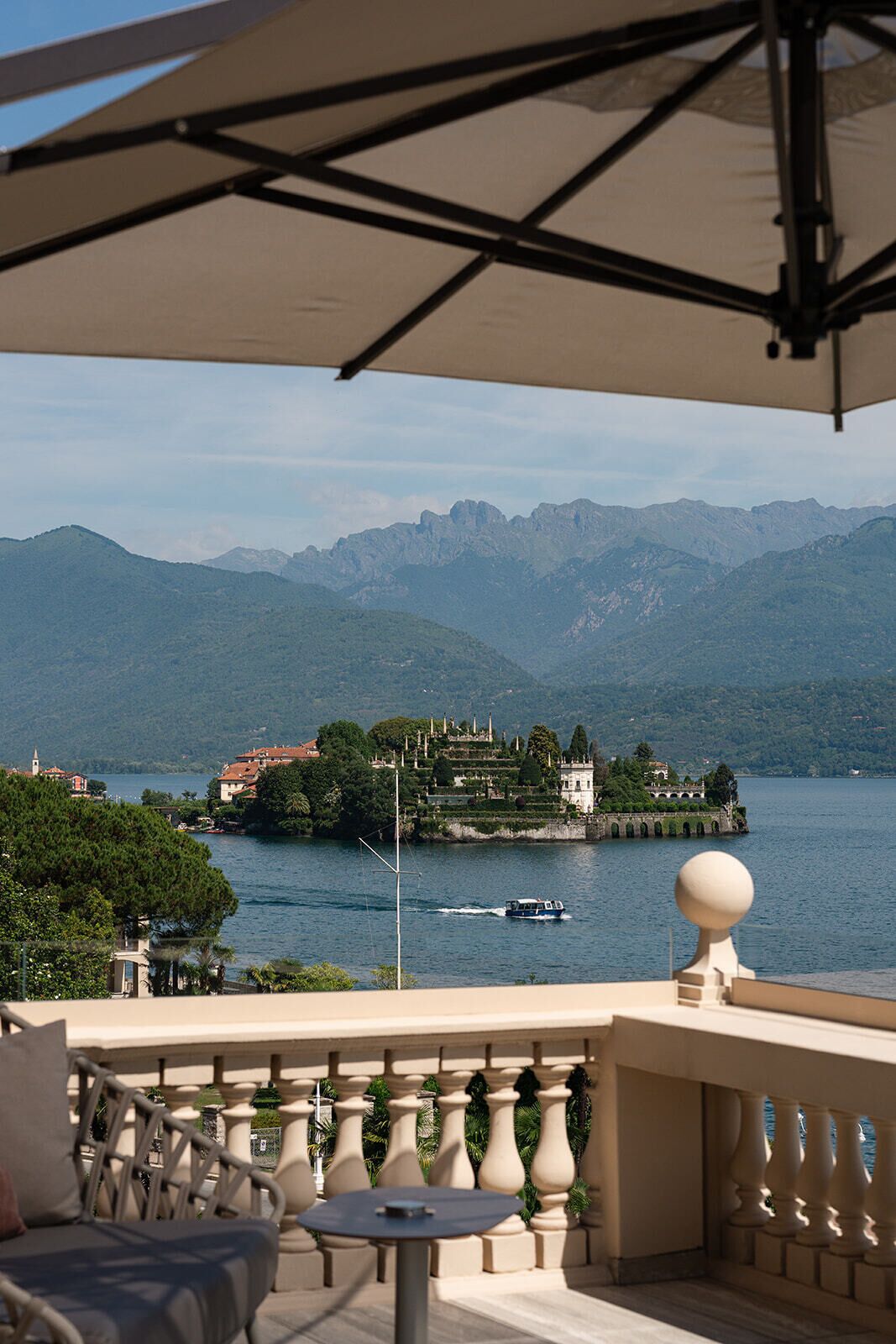 Una terrazza con vista su un lago e montagne, una barca sull'acqua e mobili da esterno.