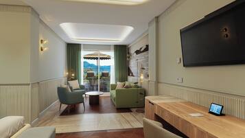 A modern hotel room with a large TV, a wooden desk, a green sofa, and a view of mountains.