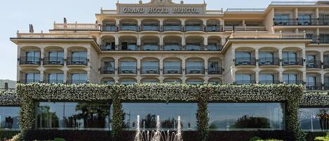 A large hotel with multiple balconies and a central fountain.