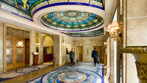 Un amplio vestíbulo con un techo circular de vitrales, suelos de mármol y arquitectura clásica.