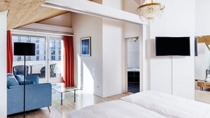 Una habitación de hotel moderna con una cama grande, un sofá, un televisor y una araña.