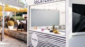 Una heladería con fachada blanca y un cartel que dice 'GELATERIA'.