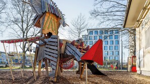 Un parque infantil con una estructura de madera que incluye un tobogán y columpios.