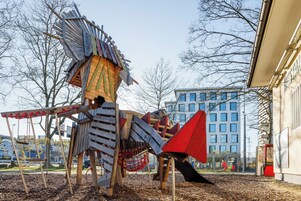Un parque infantil con una estructura de madera que incluye un tobogán y columpios.