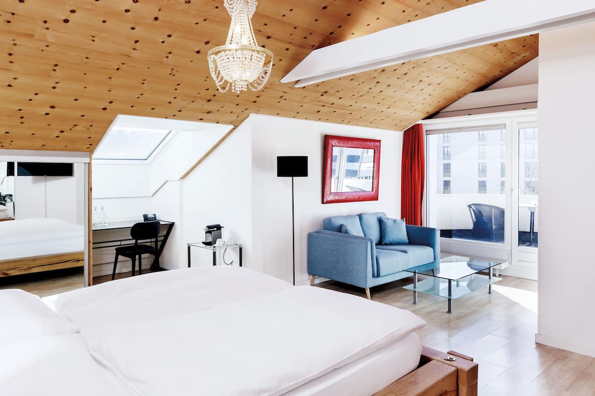 Un dormitorio moderno con una cama grande, un escritorio, un sofá azul y una mesa de centro de vidrio.