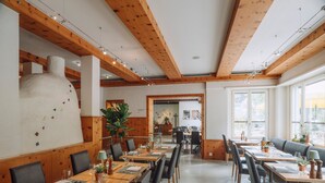 Un restaurant avec des poutres en bois, des tables et des chaises, et une grande cheminée blanche.