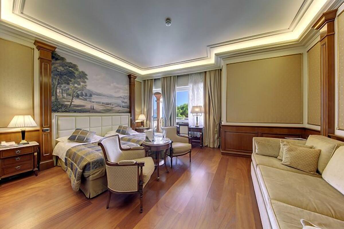 A hotel room with a bed, two armchairs, a sofa, a small table, and a painting on the wall.