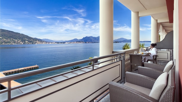 A balcony with wicker furniture overlooking a lake and mountains. - Hotel Splendid (Baveno)