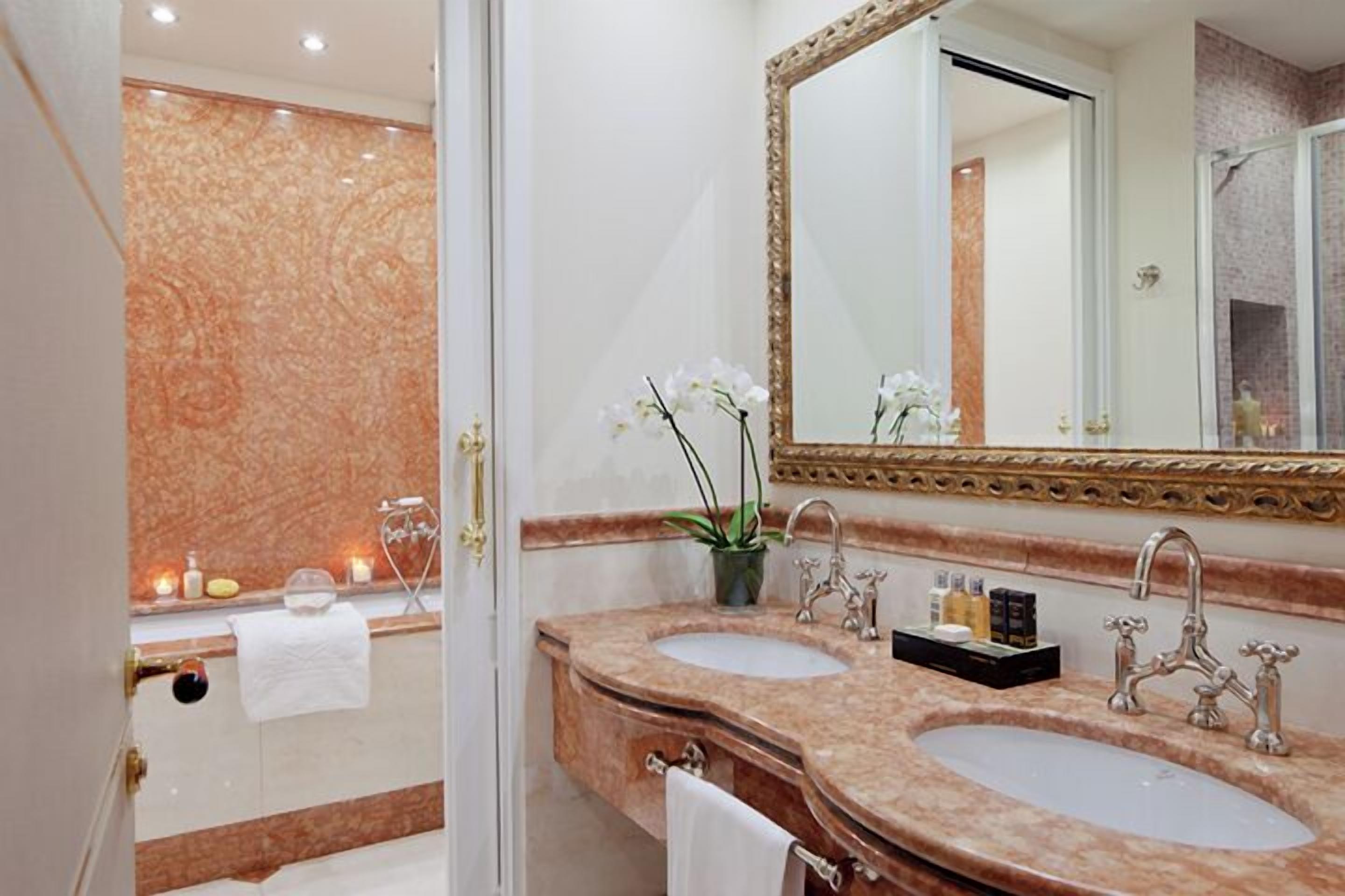 A bathroom with two sinks, a large mirror, and a vanity with a plant.
