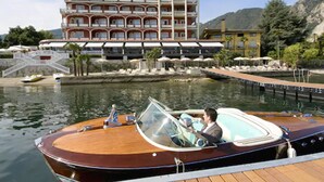 A wooden boat docked at a marina with a large hotel in the background. - Hotel Splendid (Baveno)