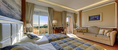 A hotel room with two beds, a sofa, a desk, and a large window with a view.