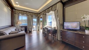 A spacious living room with a sofa, a desk, and a television. - Hotel Splendid (Baveno)