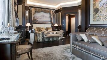 A luxurious room with a large bed, a sofa, a desk with a chair, and a large painting on the wall.