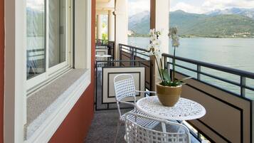 A balcony with a table and chairs, overlooking a lake with mountains in the background.