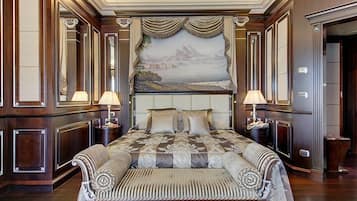 Uma cama grande com cabeceira, duas mesas de cabeceira e um banco ao pé da cama.