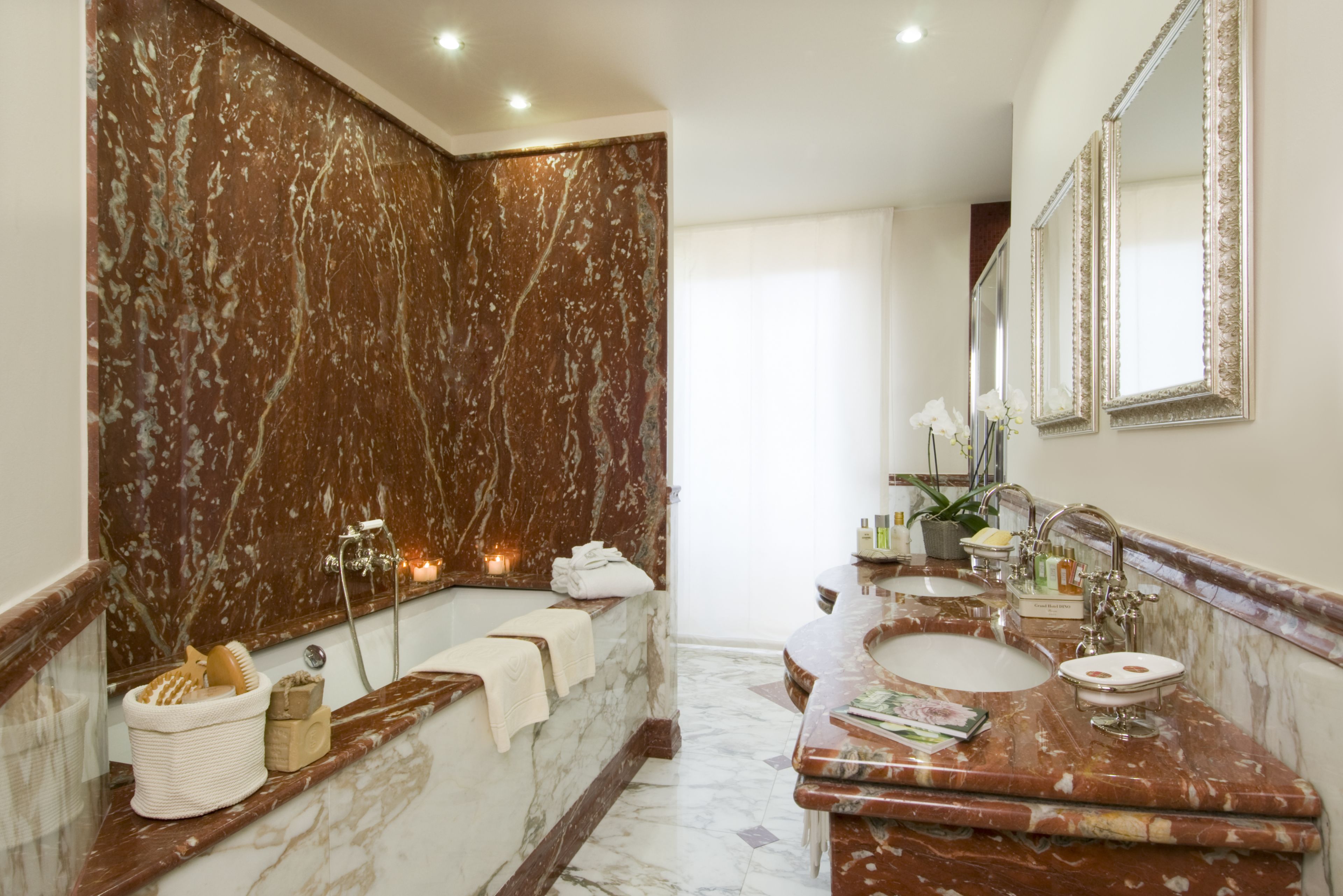A marble bathroom with a bathtub, two sinks, and a large mirror.