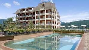 A hotel with a large pool, multiple balconies, and a view of mountains. - Hotel Splendid (Baveno)
