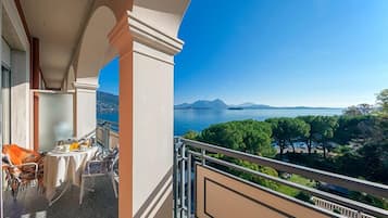 Varanda com uma mesa posta para refeições, oferecendo uma vista panorâmica de um lago e montanhas.