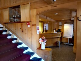 Interior de madera con una escalera, una recepción y una pizarra.